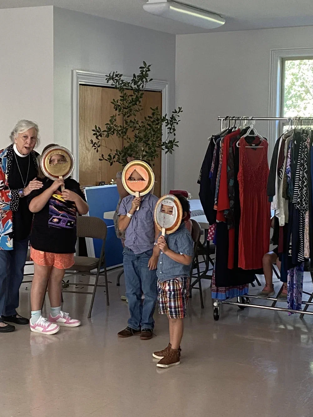 Children hold painted paper-plate masks over their faces during a Children's Chapel lesson