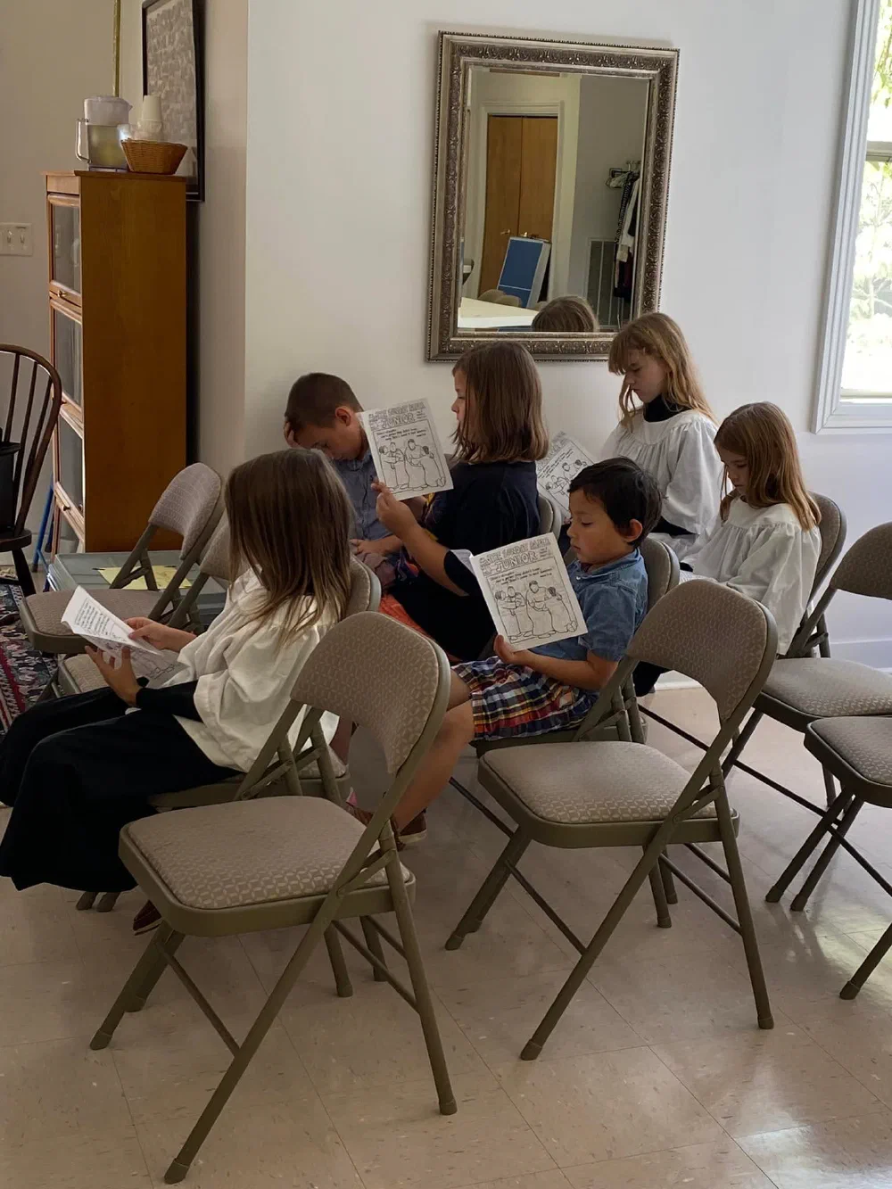 Children seated on folding chairs reading their Children's Chapel bulletins