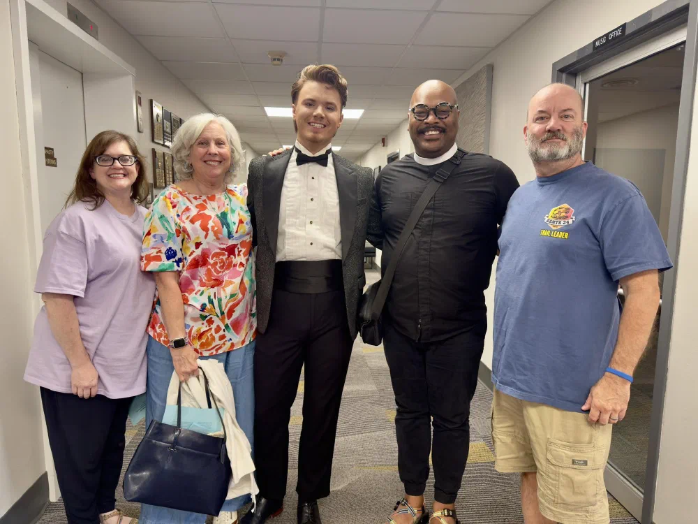 Parishioners with a young singer in his tuxedo backstage by the music office