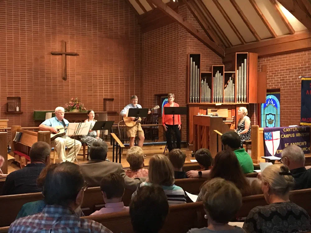 A folk ensemble with guitars and singers performs at the chancel steps before a full nave